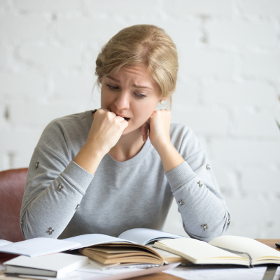femme qui se mord le poing devant ses livres