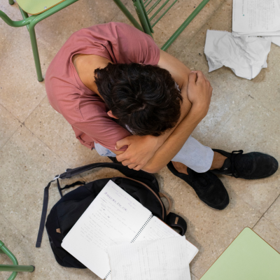 garçon par terre se tenant les genoux plein de feuille autour