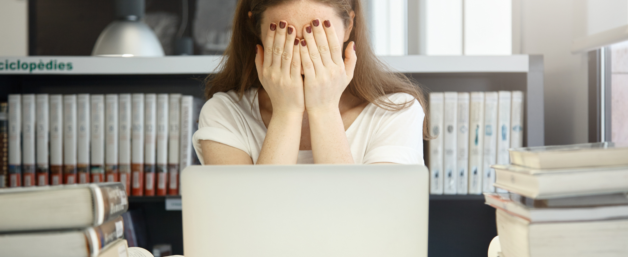 femme qui se met les mains devant les yeux devant un ordinateur